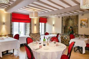 un restaurante con mesas blancas y sillas rojas en Logis Hotel Au Site Normand, en Clécy