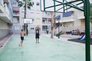 dos jóvenes jugando baloncesto en una cancha de baloncesto en Pretty Studio With Swimming Pool, en Torrevieja
