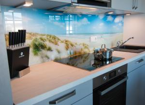 a kitchen with a counter with a sink and a painting at Fewo Strandleben Haus Strandperle in Börgerende-Rethwisch