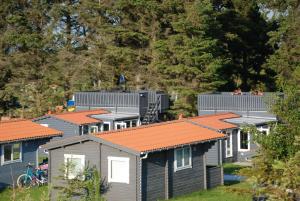 une rangée de maisons modulaires avec toits orange dans l'établissement Hytteby – Hanstholm Camping – Thy Feriepark, à Hanstholm