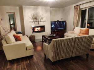 een woonkamer met 2 witte stoelen en een tv bij Brona Dempsey in Birr