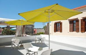 a patio with tables and chairs and yellow umbrellas at Stavros Pension in Rhodes Town