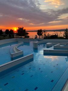 a large swimming pool with a sunset in the background at Velence Wellness Apartman in Velence