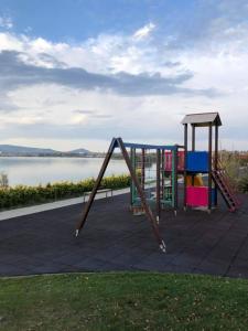 a playground with a swing set next to a body of water at Velence Wellness Apartman in Velence