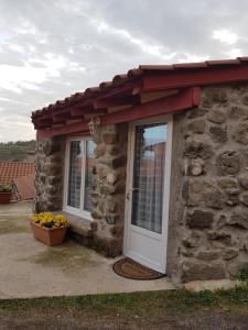 a stone building with a white door and a red roof at La maison D'Orée in Polignac