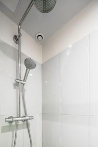 uma cabeça de chuveiro numa casa de banho com azulejos brancos em Emmanuel & Béatrice em Paris