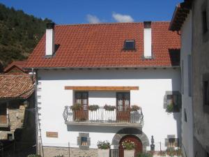 a white building with a balcony with flowers on it at Casa rural Ornat Etxea in Vidángoz