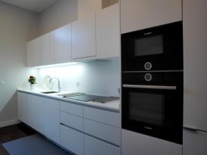 ポルトにあるCool Terrace Apartmentの白いキャビネットと黒の電化製品が備わるキッチン