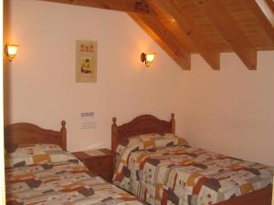 two beds in a bedroom with wooden ceilings at Casa rural Ornat Etxea in Vidángoz