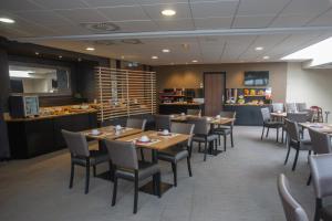 a dining room with tables and chairs and a counter at Mercure Vannes Le Port in Vannes