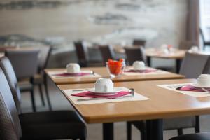 une rangée de tables en bois avec des serviettes et des chapeaux dans l'établissement Mercure Vannes Le Port, à Vannes