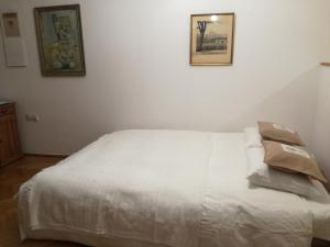 1 cama blanca en una habitación con 2 cuadros en la pared en Pokój z widokiem, en Cracovia
