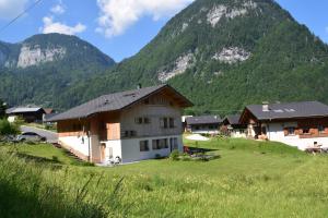 ein Haus auf einem Feld mit Bergen im Hintergrund in der Unterkunft Apartment La Tibolire in Sixt