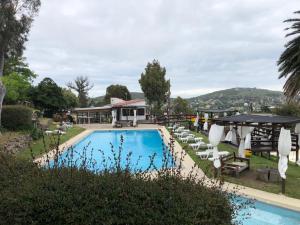 a pool with chairs and umbrellas next to a house at Complejo Laderas del Cerro in Piriápolis