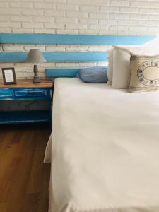 Blu Inn في بونتا دل إستي: غرفة نوم مع سرير أبيض مع اللوح الأمامي الأزرق