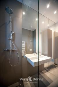 La salle de bains est pourvue d'un lavabo blanc et d'une douche. dans l'établissement Very Berry - Orzeszkowej 14 - MTP Apartment, parking, check in 24h, à Poznań