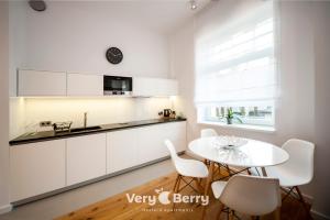 une cuisine avec des placards blancs et une table et des chaises blanches dans l'établissement Very Berry - Orzeszkowej 14 - MTP Apartment, parking, check in 24h, à Poznań