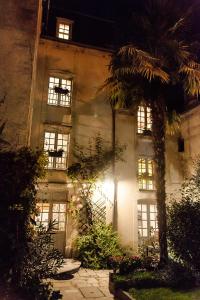 un bâtiment avec un palmier en face dans l'établissement Manoir Sainte Victoire, à Bayeux