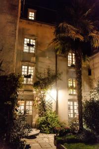 a building with a palm tree in front of it at Manoir Sainte Victoire in Bayeux