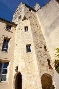 un grand bâtiment en pierre avec une tour en haut dans l'établissement Manoir Sainte Victoire, à Bayeux
