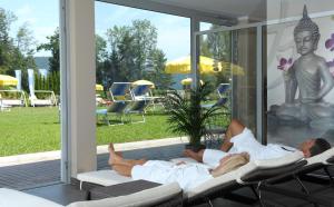 dwóch mężczyzn leżących na krzesłach na patio w obiekcie Dei Hotel Schönblick w mieście Velden am Wörthersee