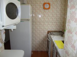 uma pequena cozinha com um frigorífico e um relógio na parede em Recanto Santista em Santos