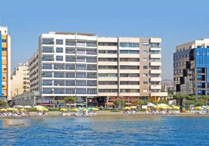 une plage avec des chaises et des parasols et un grand bâtiment dans l'établissement Eden beach apartment 111, à Limassol