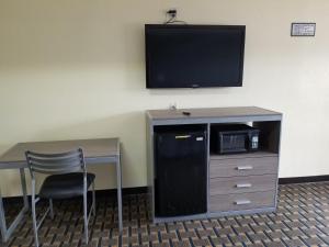 a room with a desk and a tv on a wall at Economy Inn Motel in Orange