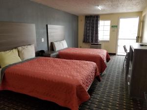 a hotel room with two beds and a television at Ameristay Inn & Suites in Orange