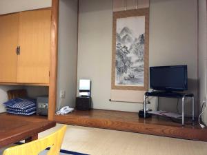 sala de estar con TV sobre una mesa de madera en Saihokuso inn en Ueda