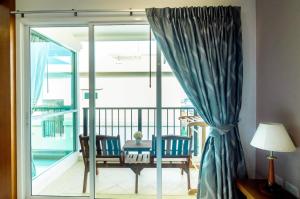 Habitación con puerta corredera de cristal, mesa y sillas. en G Residence en Pattaya South
