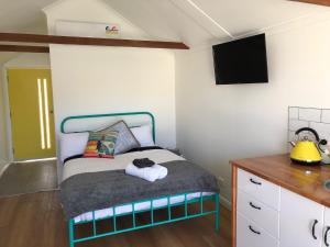 a bedroom with a bed with a tv on the wall at Tiny Tom - Hidden beside the river Mersey in Devonport +5 photos