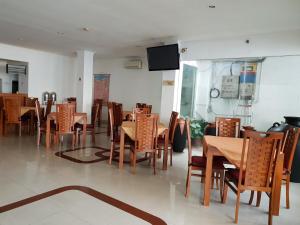 une salle à manger avec des tables, des chaises et une télévision dans l'établissement Hotel Caravan, à Jakarta