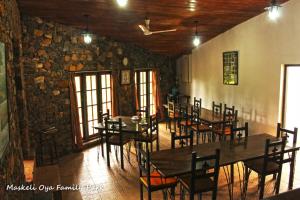 uma sala de jantar com mesas e cadeiras e uma parede de pedra em Maskeli Oya Family Park em Norton Bridge