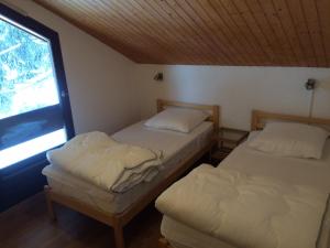 two beds in a room with a window at HAMEAU DU RUISSEAU in Manigod