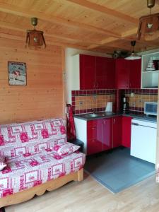 a kitchen with red cabinets and a bed in a room at MONT BLANC SOLEIL E-2 in Manigod