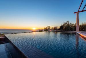 a swimming pool with the sunset in the background at A brand NEW VILLA - Infinity in Podstrana +33 photos