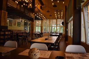 a restaurant with wooden tables and chairs and windows at B&B Bela Vrba in Bačko Novo Selo
