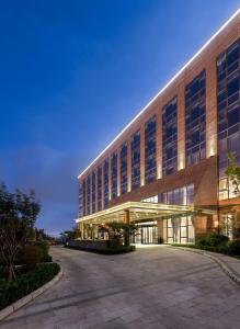 a large building with a parking lot in front of it at Novotel Qingdao New Hope in Qingdao