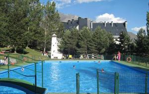 a large swimming pool in a park with a castle in the background at Ski & relax Apartment in Formigal
