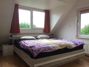 スカーレンデイケにあるFerienhaus Nordseeliebeの窓が2つある寝室のベッド