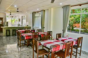 Villa Gamini في هيكادوا: مطعم به طاولات وكراسي حمراء وبيضاء