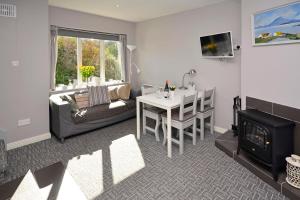 een woonkamer met een bank, een tafel en een open haard bij Cottage 315 - Clifden in Clifden