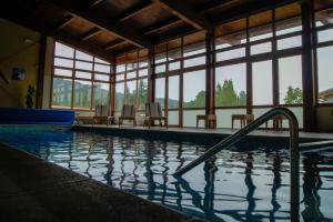 a large swimming pool with chairs and windows at Las Cabañas in Vegaquemada