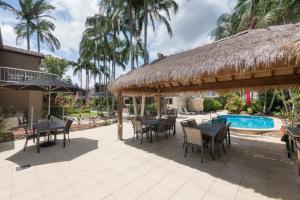 a patio with tables and chairs and a straw umbrella at Durramboi Luxury Apartment in Noosaville