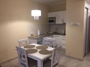 a kitchen with a table and chairs and a refrigerator at Etna Polonia Apartamenty in Kołobrzeg