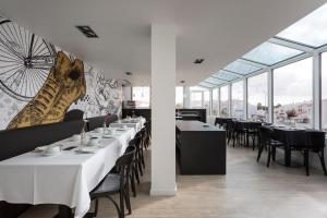 un restaurant avec des tables blanches, des chaises et des fenêtres dans l'établissement Sport Hotel A Seleção, à Setúbal