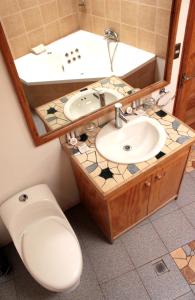 a bathroom with a sink, toilet and mirror at Hotel Poblado Kimal in San Pedro de Atacama
