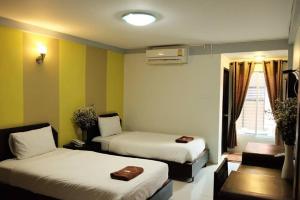 um quarto de hotel com duas camas e uma janela em Puangpech Place em Lampang