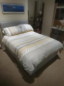 - un lit dans une chambre avec une couette à rayures dans l'établissement 8A Kenilworth Road, à Portsmouth